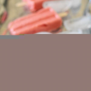 Stack of strawberry coconut milk popsicles on a silver tray with ice cubes, ready to eat.