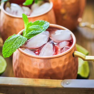 Strawberry Moscow mules in a wooden serving tray with fresh lime leaves, ready to serve.