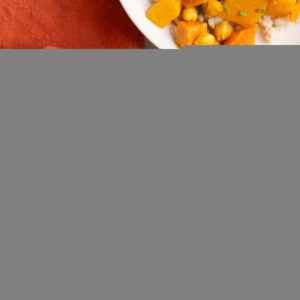 Butternut Squash and Yam Curry in a white bowl with a wood inlay fork and a red napkin to the side.