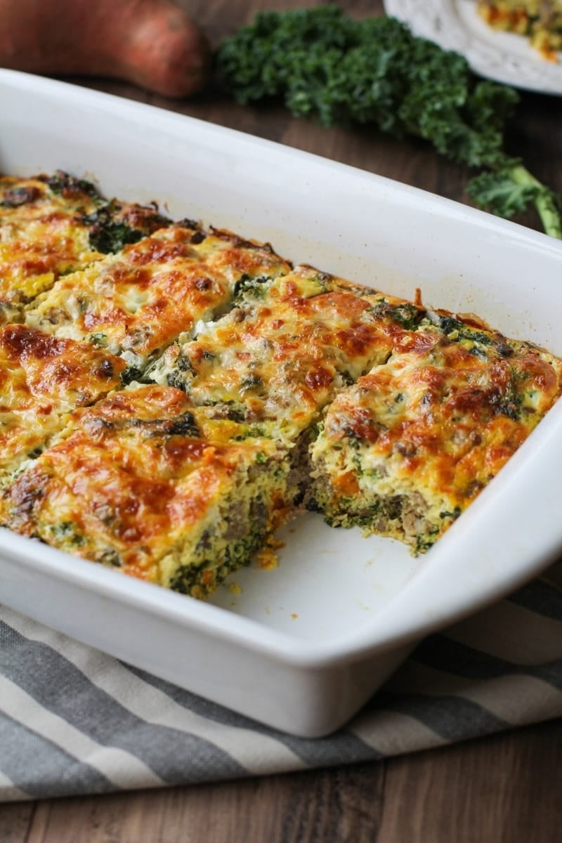 Sweet potato and sausage egg casserole in a baking dish with a piece missing, fresh out of the oven.