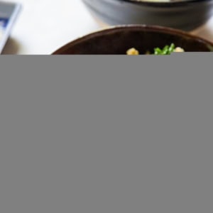 Big ceramic blue bowl full of sauteed vegetables, rice, and a teriyaki salmon filet sprinkled with sesame seeds. Ready to eat!