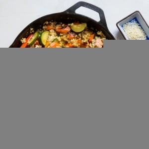 Teriyaki Stir Fry Vegetables with Rice in a cast iron skillet with two sets of chop sticks to the side.