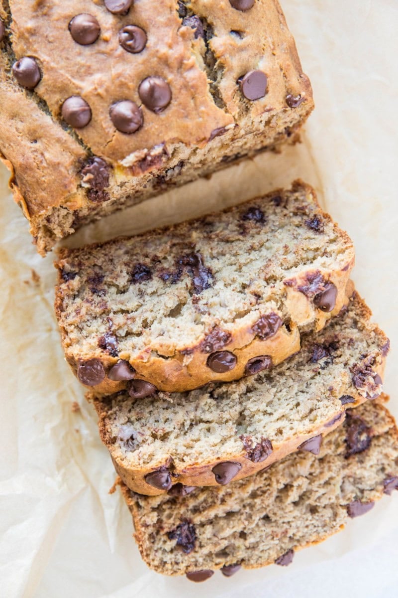 Loaf of gluten-free banana bread on a sheet of parchment paper, cut into slices.