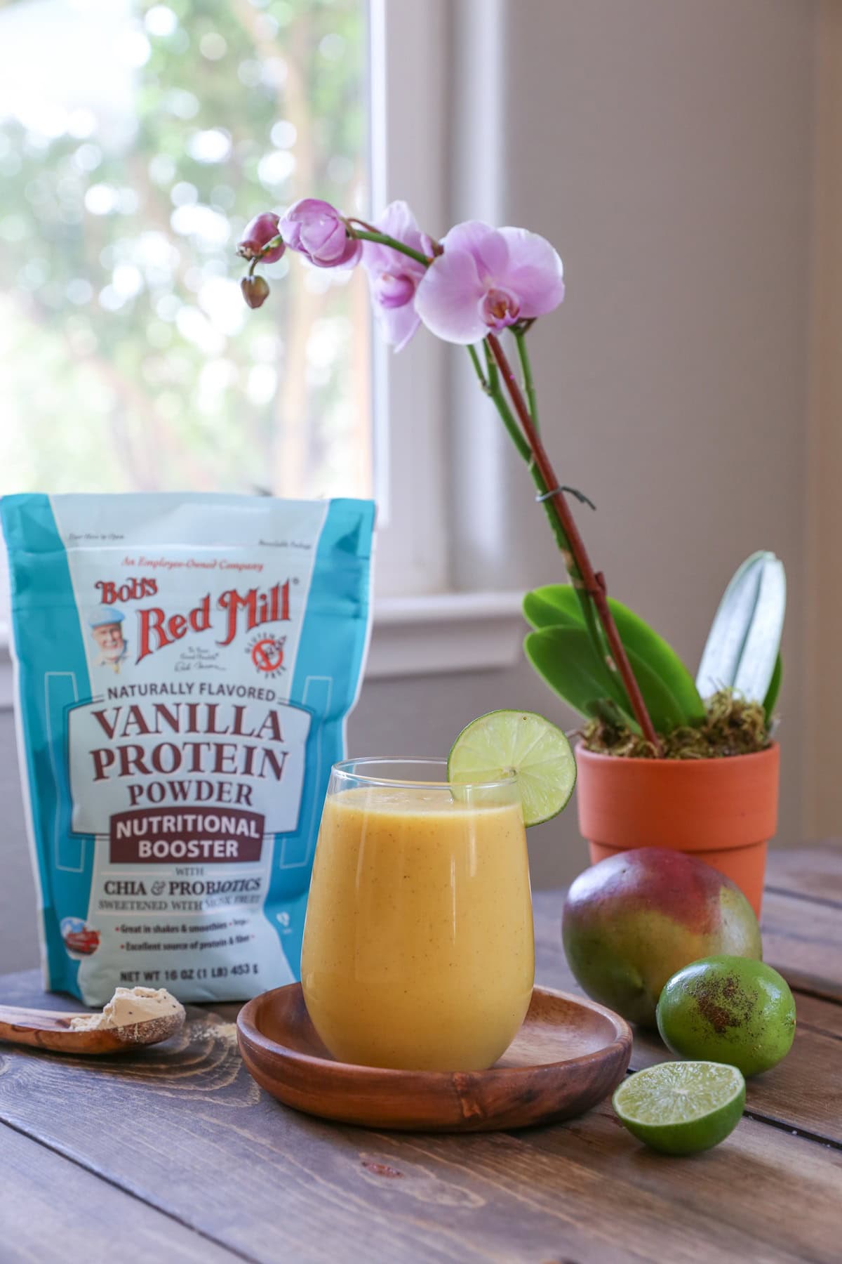 Smoothie on a wooden plate with limes to the side with vanilla protein powder
