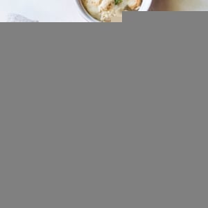 Large casserole dish full of tuna casserole fresh out of the oven with a small ramekin to the side full of a portion of casserole.