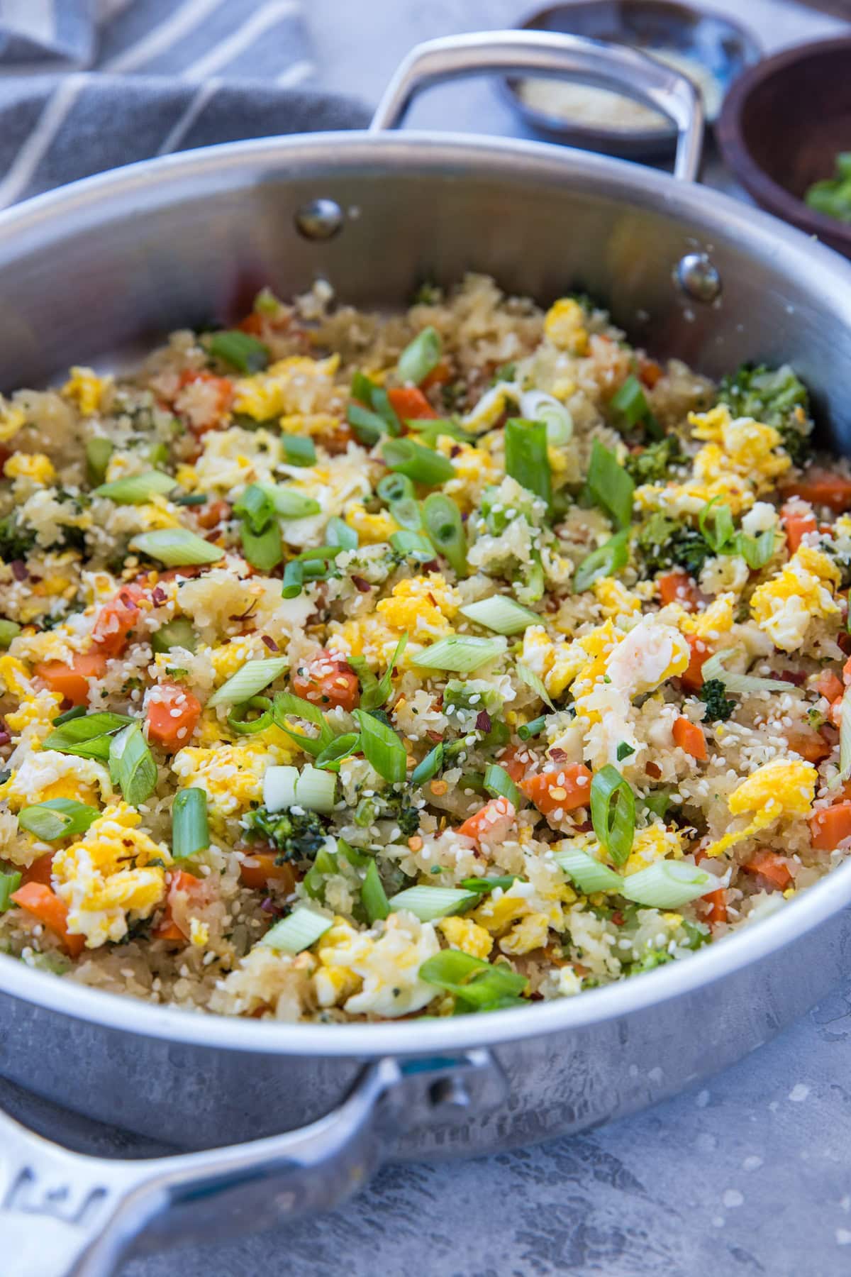 Stainless steel skillet full of turnip fried rice, sprinkled with chopped green onions.