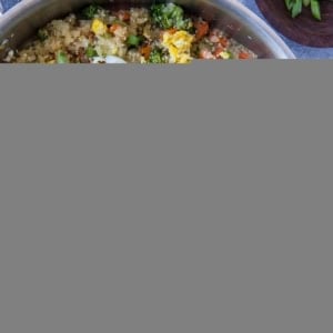 Turnip fried rice in a stainless steel skillet with a napkin and a bowl of sesame seeds to the side.