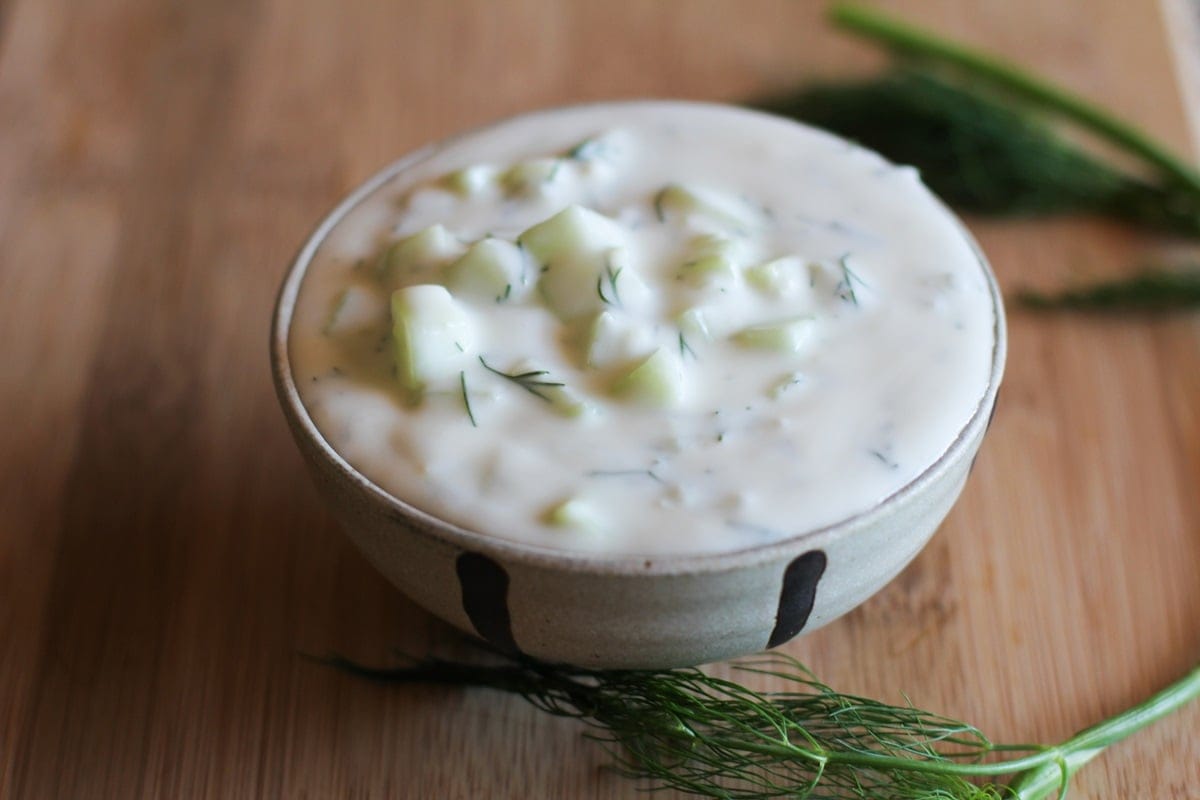 Bowl of homemade tzatziki sauce with fresh dill around. Ready to use.