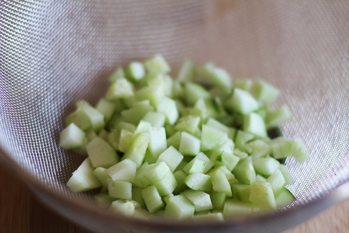 Strainer with chopped cucumber draining.