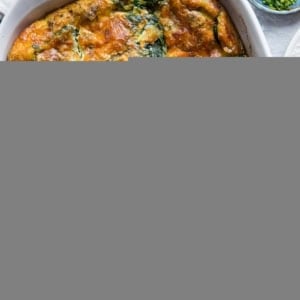 Large white casserole dish full of egg casserole with sausage and spinach, ready to serve.