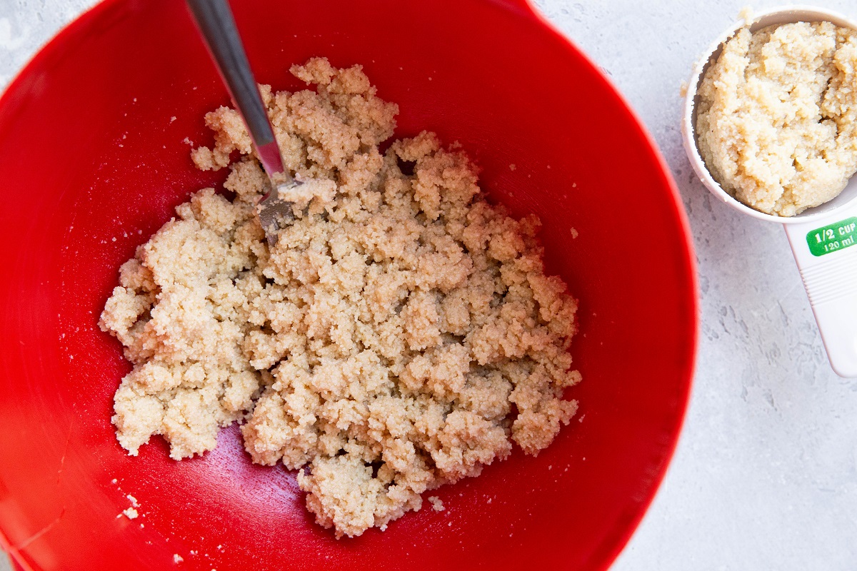 Almond flour shortbread crust in a red mixing bowl, ready to be made into bars.