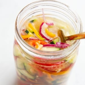 Large jar full of vegetables and vinegar solution to make quick pickled vegetables.
