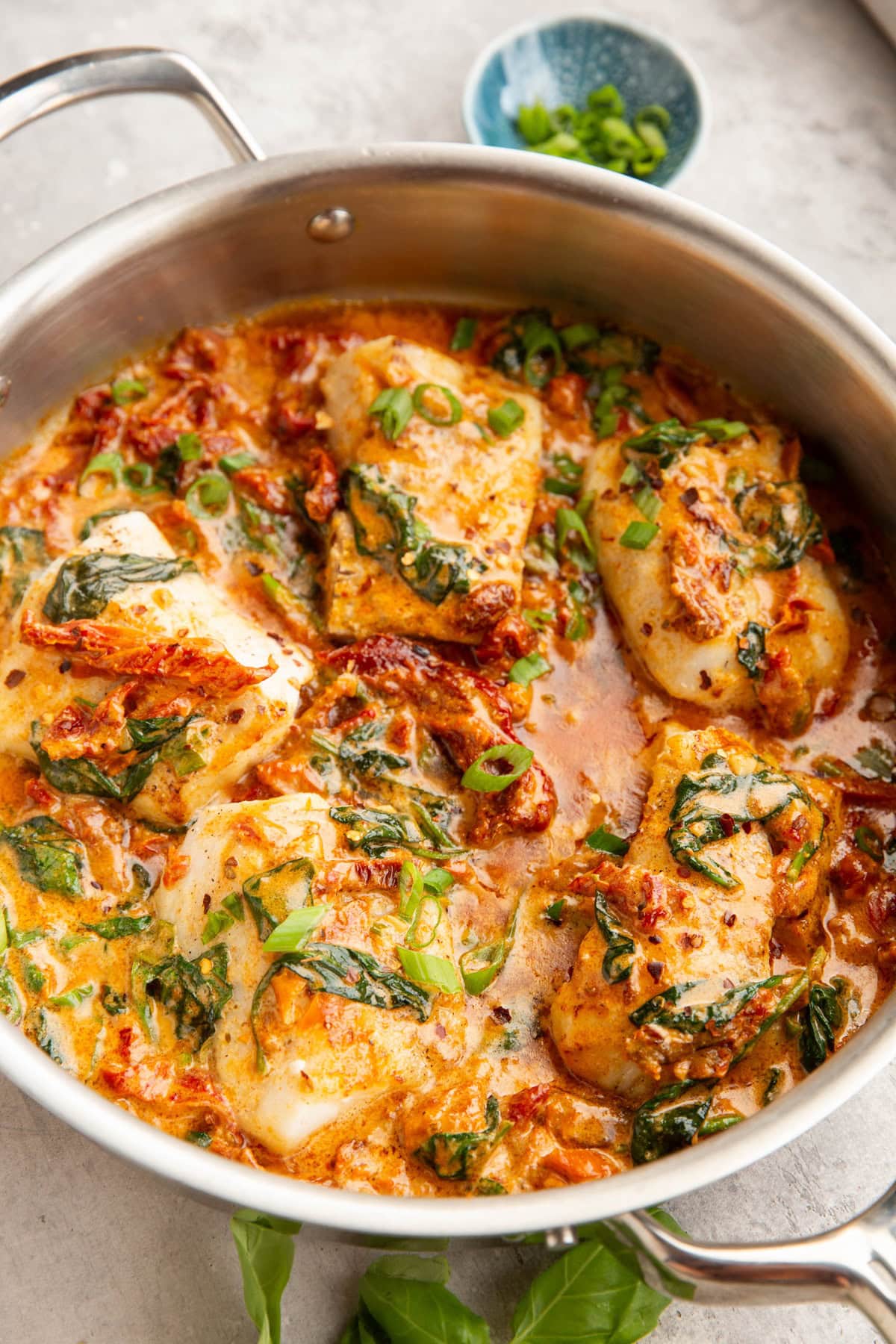 Skillet with sun-dried tomato sauce covered in cod.