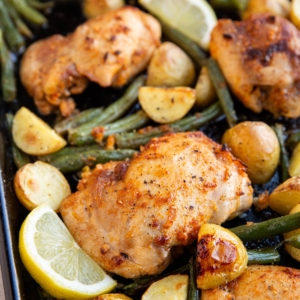 Baking sheet full of lemon chicken and vegetables.