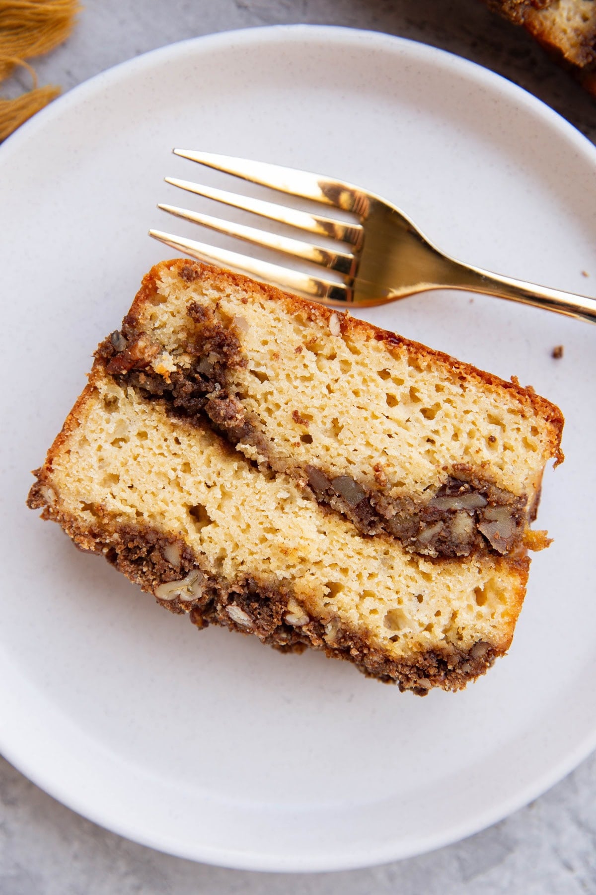 Slice of cinnamon roll bread on a plate with a fork to the side, ready to eat.