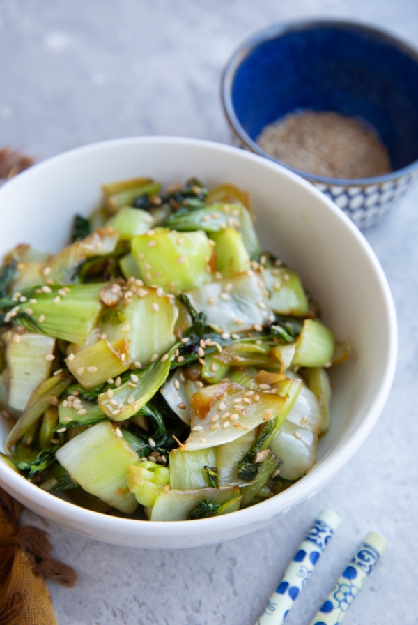Bowl full of baby bok choy with sesame seeds sprinkled on top.