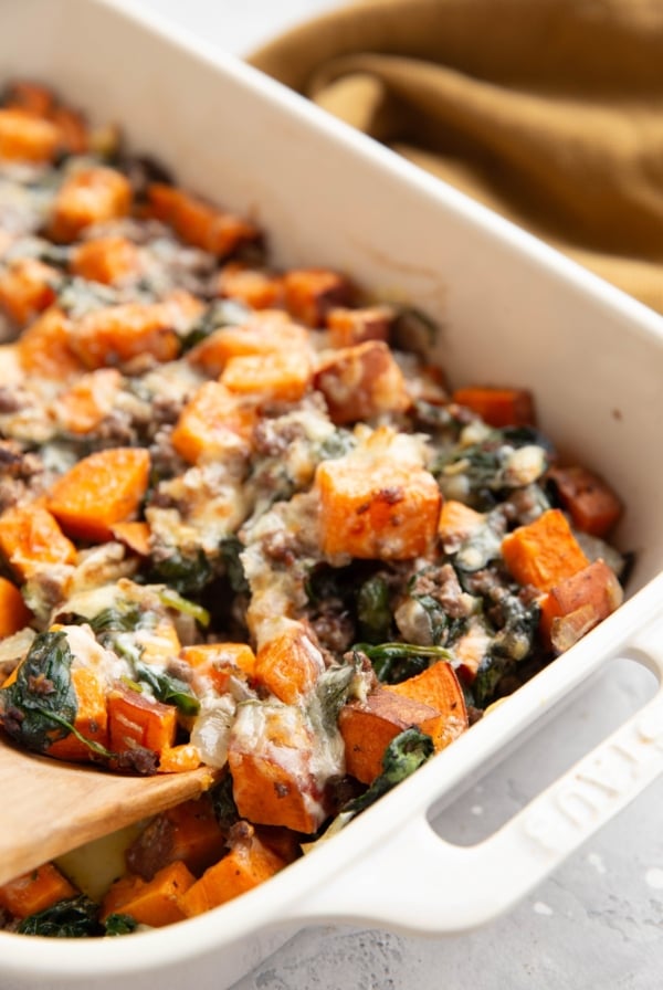 Sweet potato, ground beef, and spinach in a casserole dish.