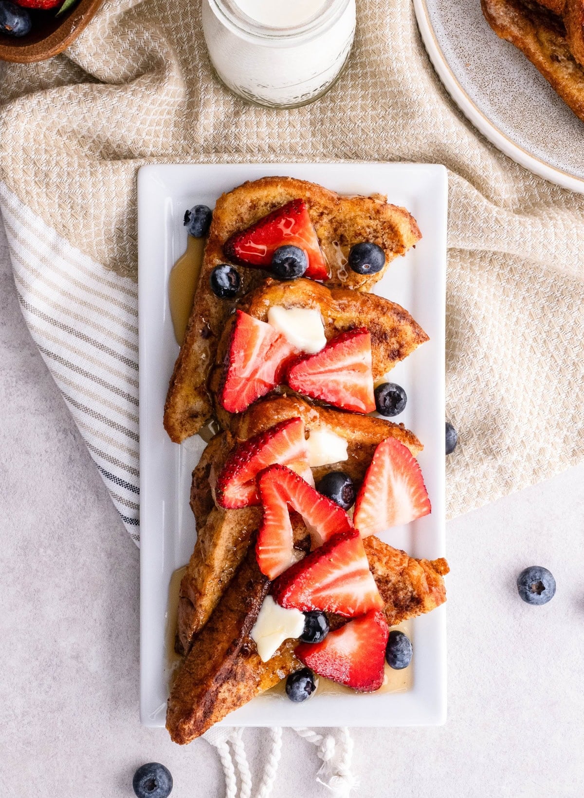Serving platter with slices of French toast with berries and butter on top. Ready to serve.