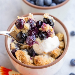 Spoonful of almond flour blueberry crisp scooping to enjoy a bite.