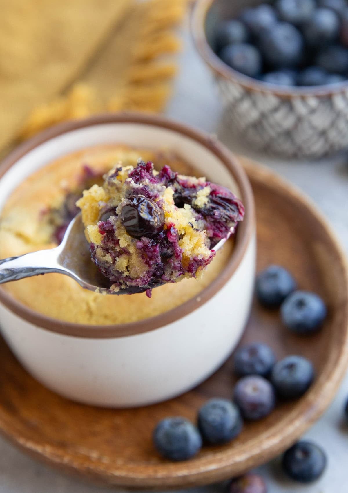 Spoon holding a scoop of blueberry muffin, ready to eat.