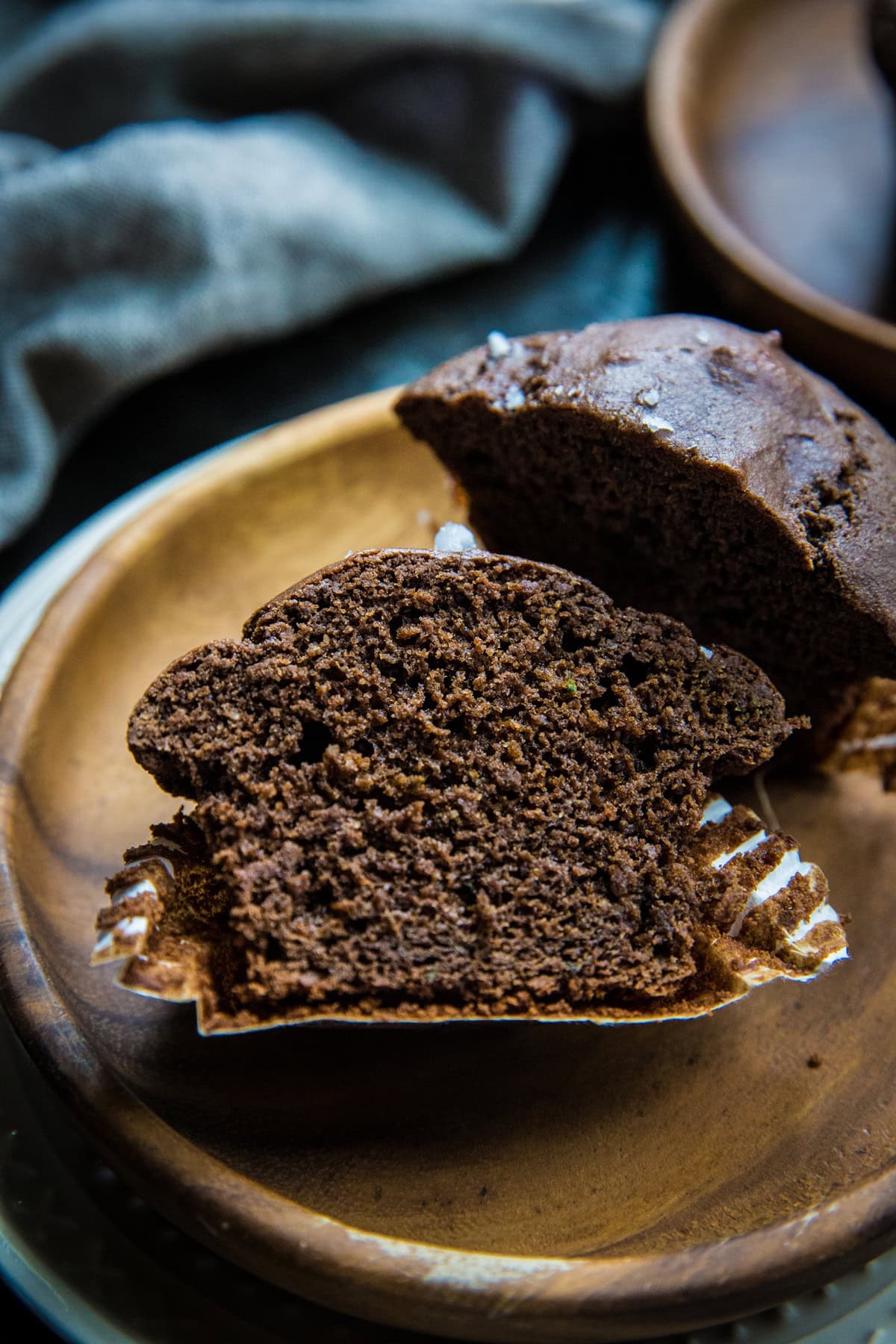 Chocolate zucchini muffin sliced in half on a plate so you can see the inside.
