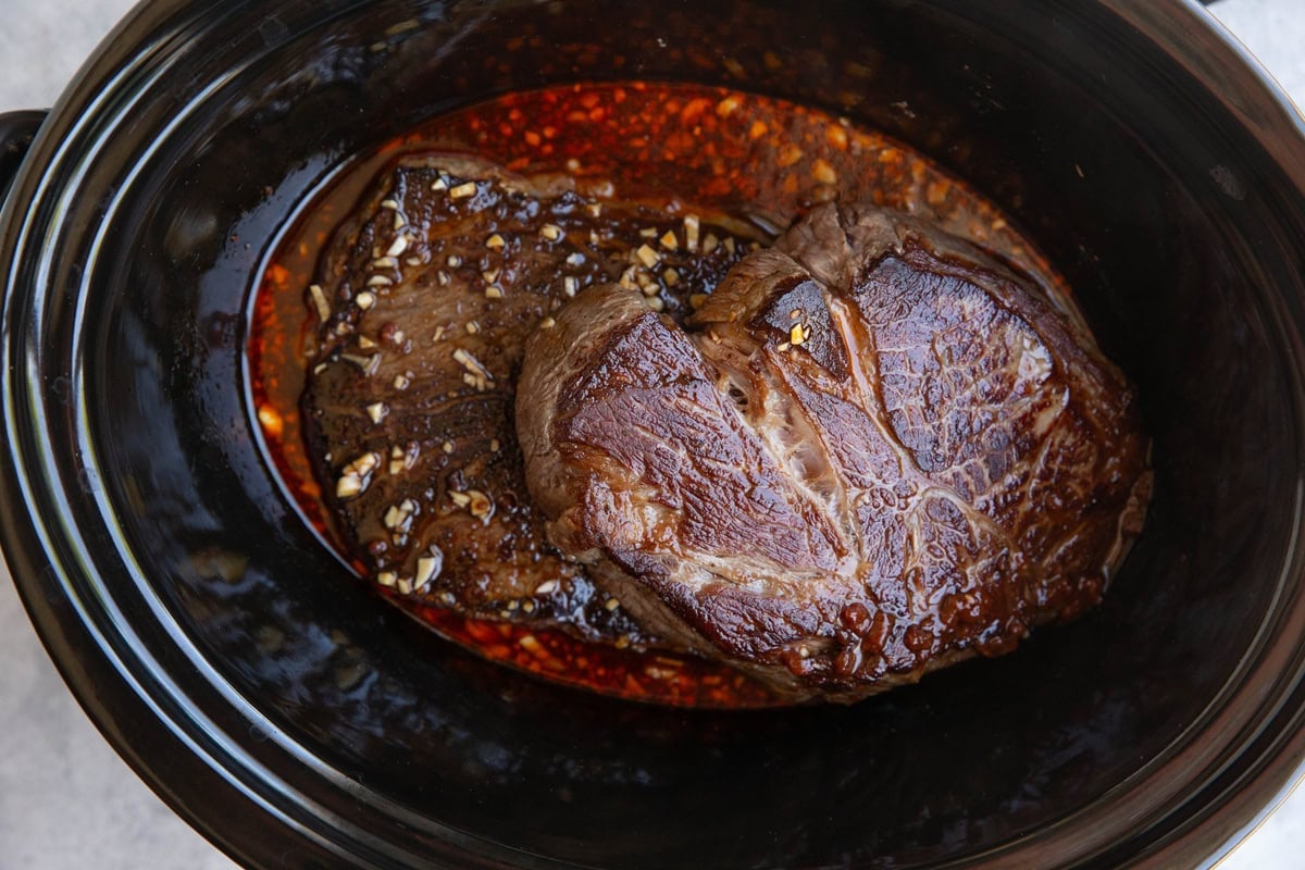 Two chuck roasts in a slow cooker with Korean bbq beef sauce.