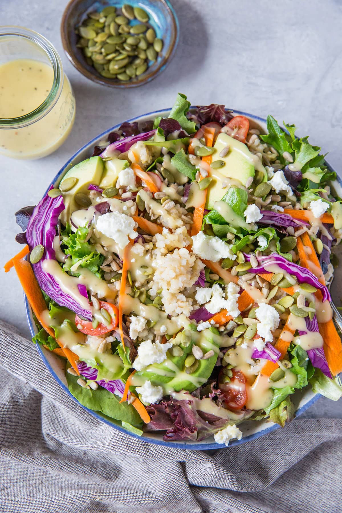 Big bowl of salad with spring greens, carrots, cabbage, pumpkin seeds, goat cheese, and more. Ready to eat!