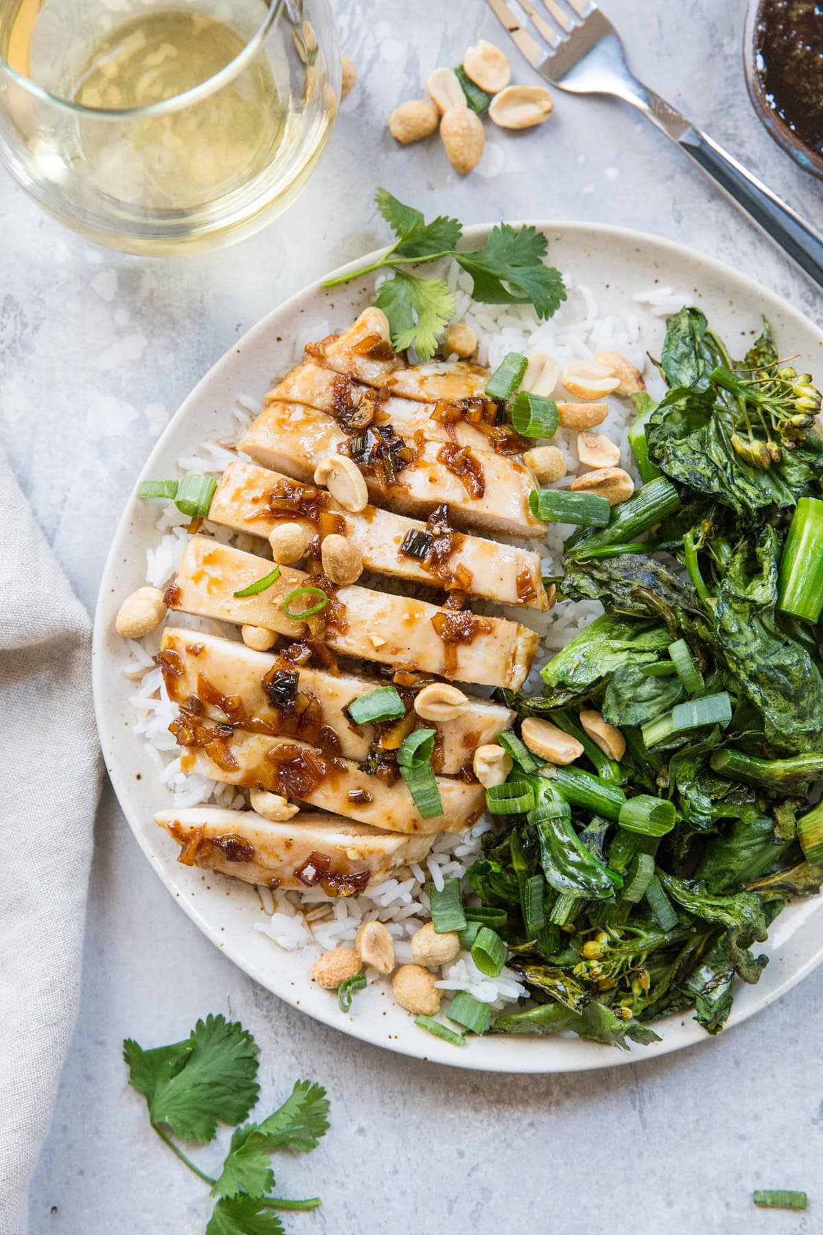 Plate of lemongrass chicken cut into slices with white rice and broccoli.