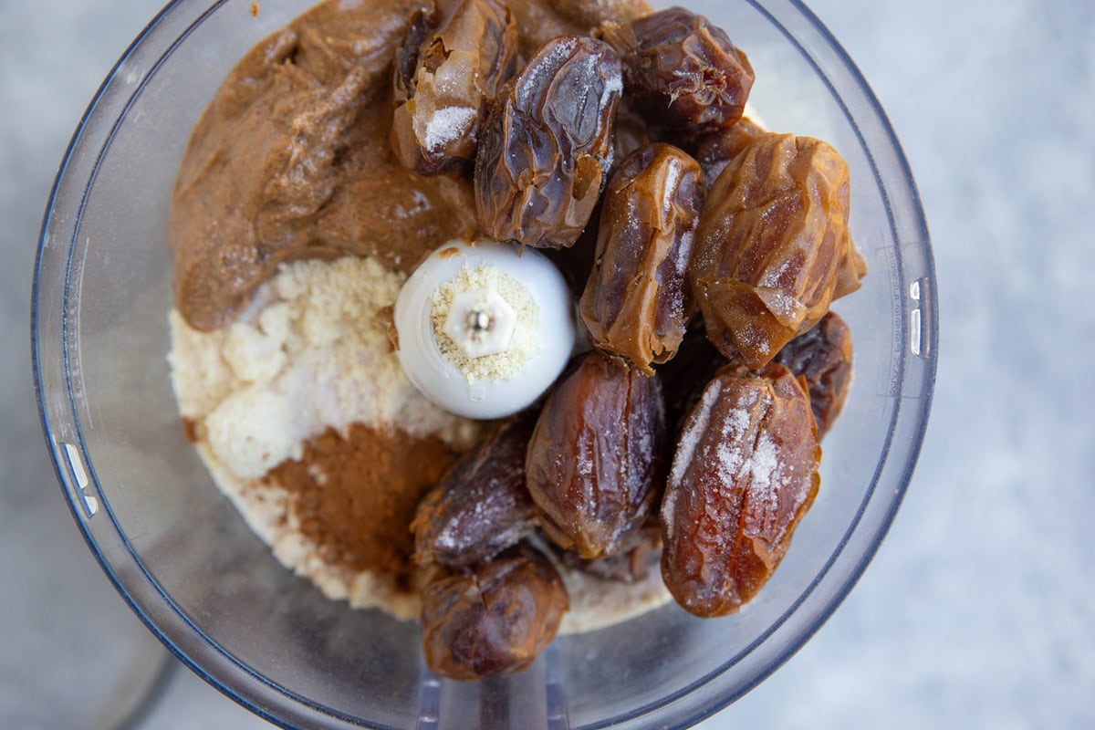 Food processor full of dates, protein powder, almond flour, almond butter, and cinnamon.