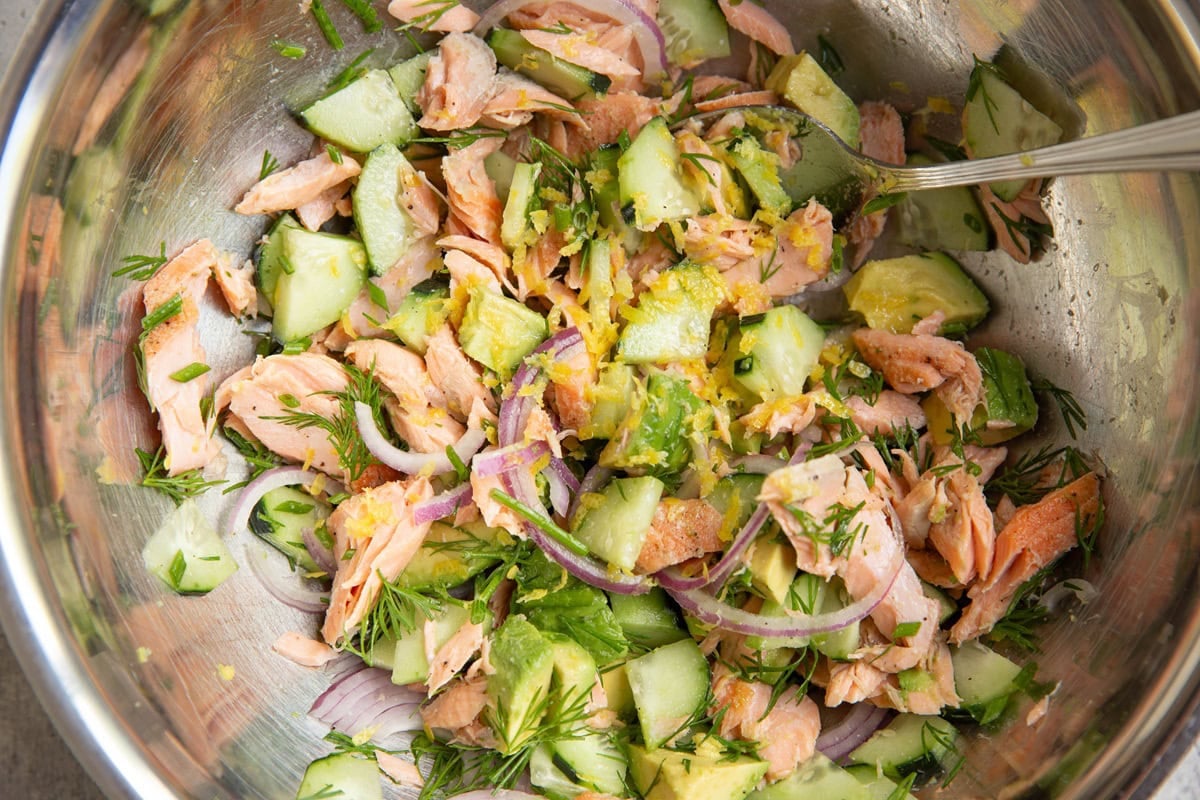 Mixing bowl with cucumber dill avocado salmon salad mixed inside, ready to eat.