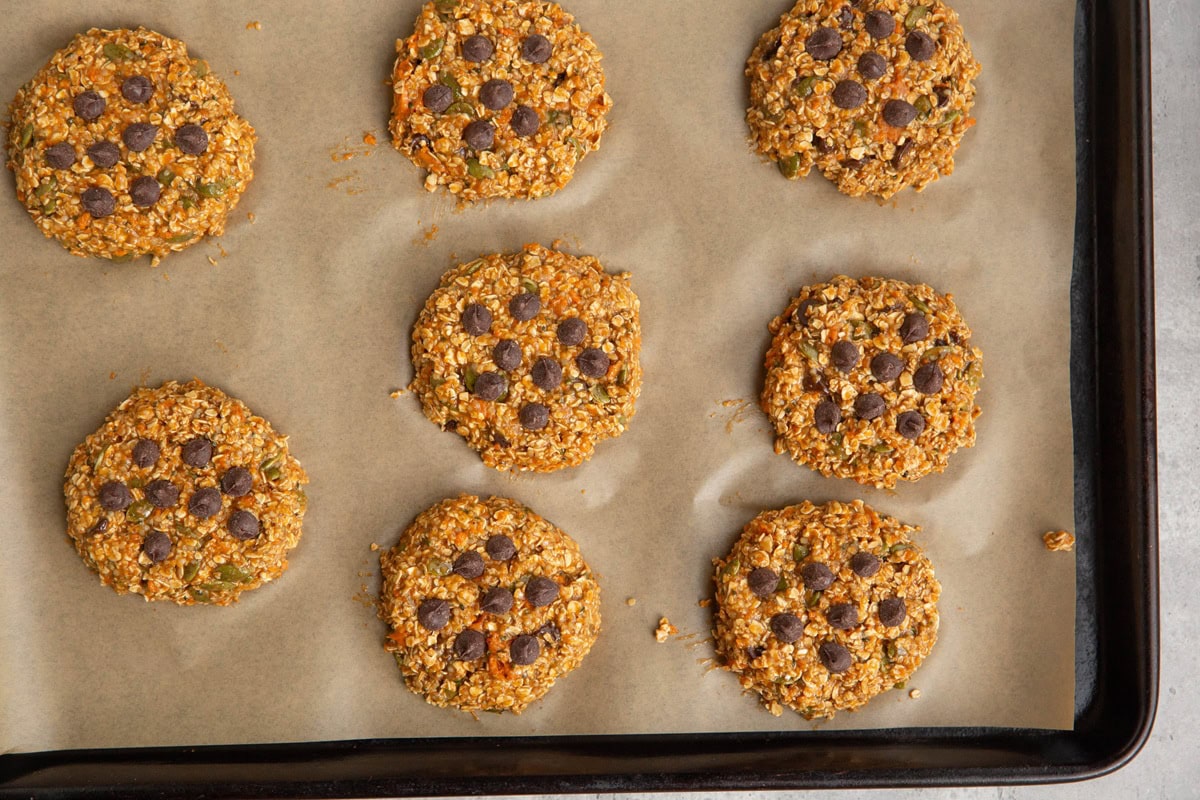 Baking sheet lined with parchment paper with sweet potato cookie dough on top, to be baked.