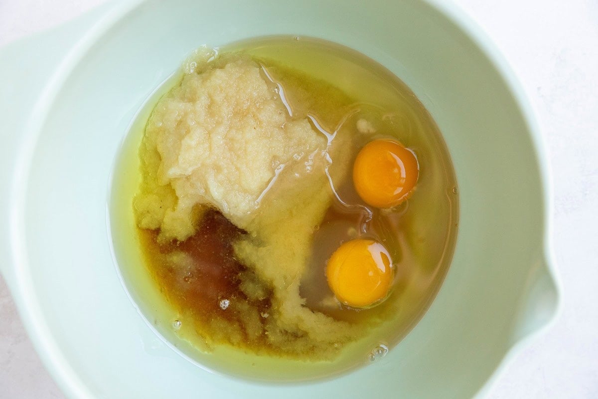 Mixing bowl of applesauce, eggs, oil, and pure maple syrup for applesauce cake.