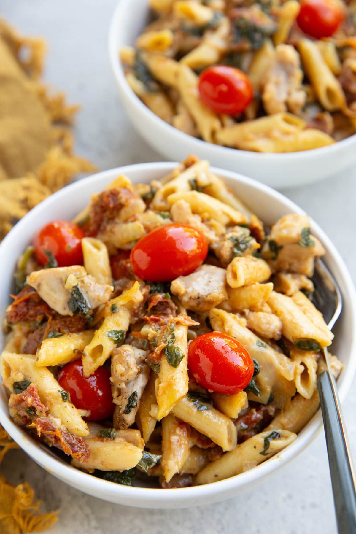 Marry me chicken pasta in two white bowls with forks and a golden napkin to the side, ready to eat.
