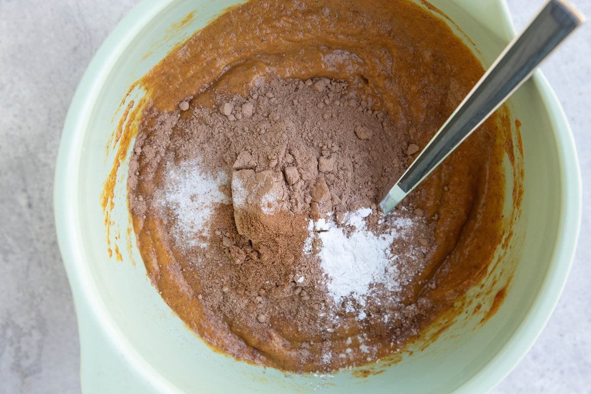 Wet ingredients in the bottom of a mixing bowl with dry ingredients on top, ready to be mixed in.