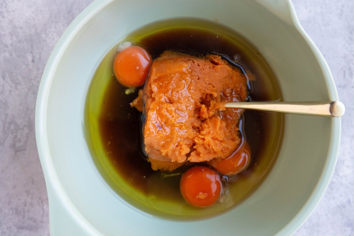 Mixing bowl of eggs, mashed sweet potato, oil, and pure maple syrup, ready to be mixed.