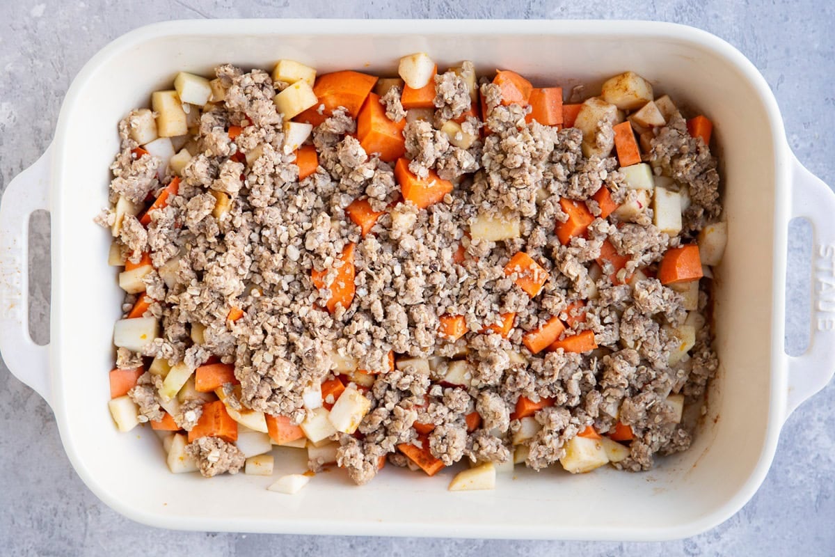 Large casserole dish full of sweet potatoes, apples, and topping to make a casserole.