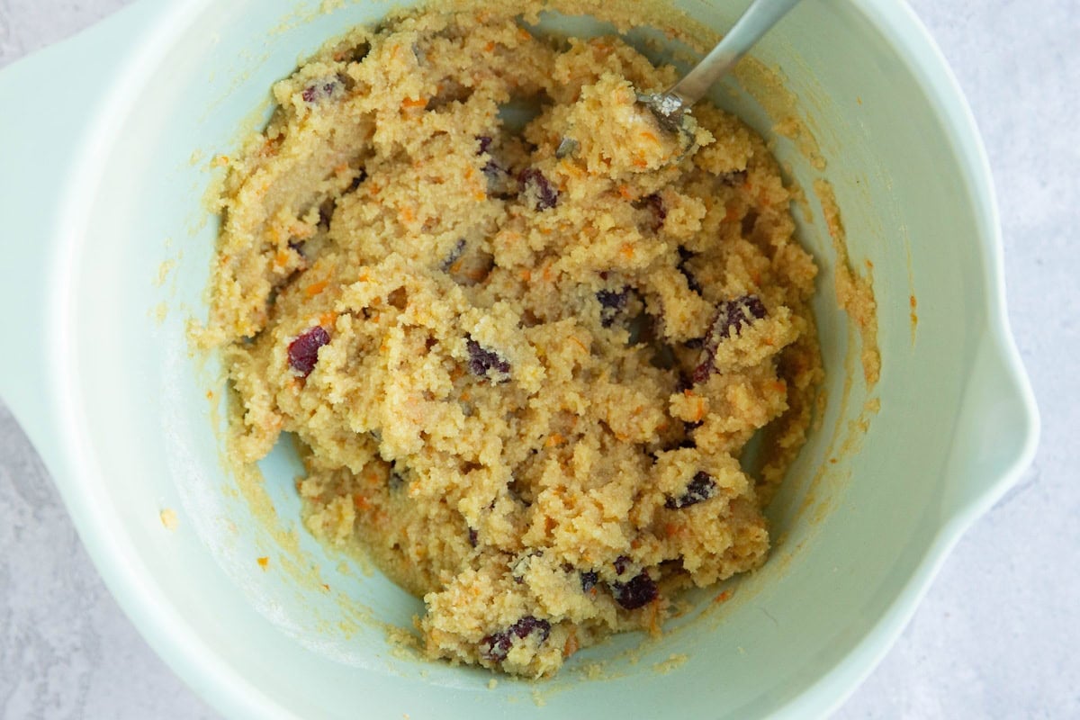 light green mixing bowl with cranberry orange cookie dough inside.