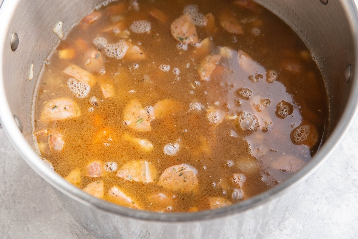 large soup pot full of soup with sausage and black eyed peas.