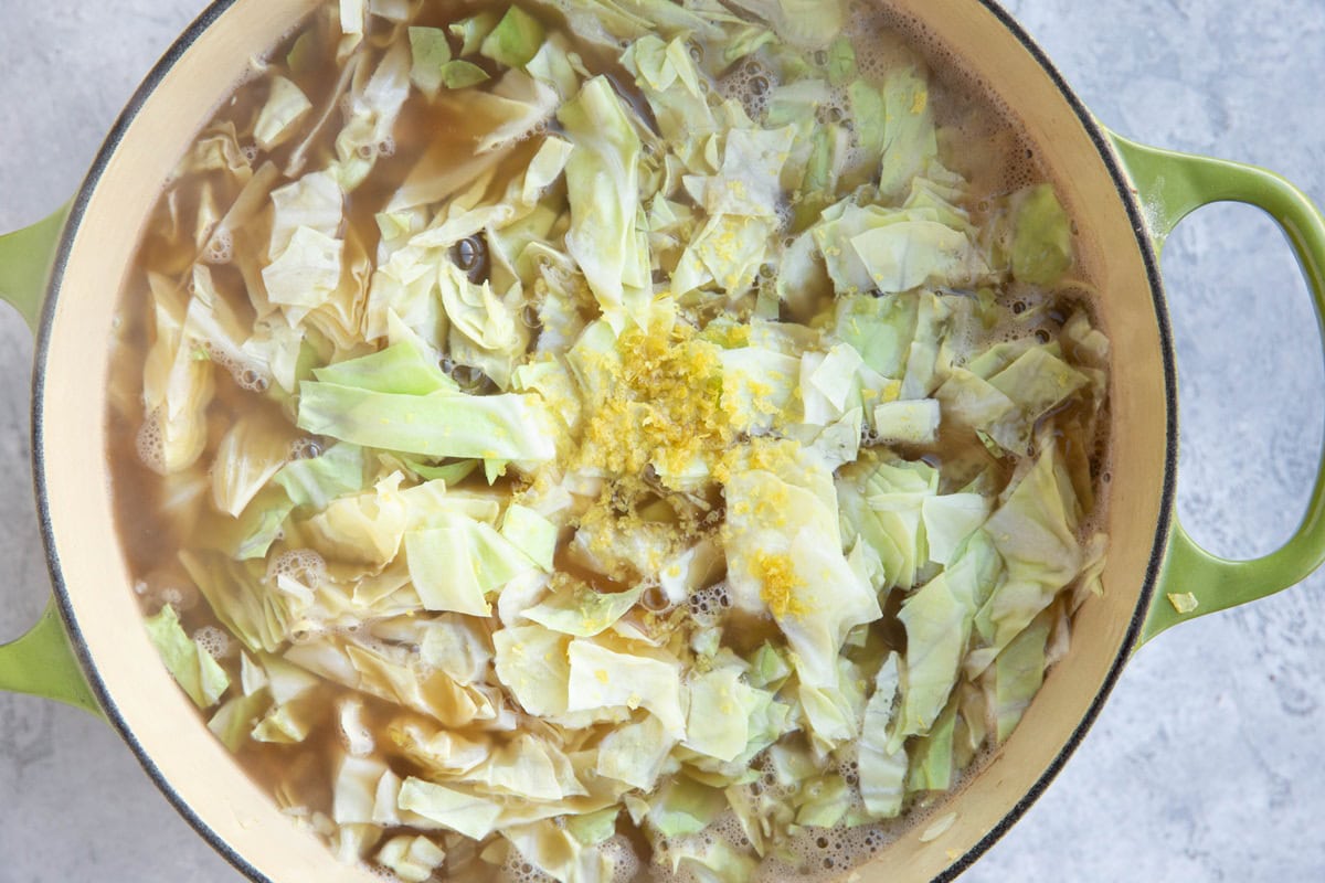 Large soup pot full of soup with cabbage and lemon zest.