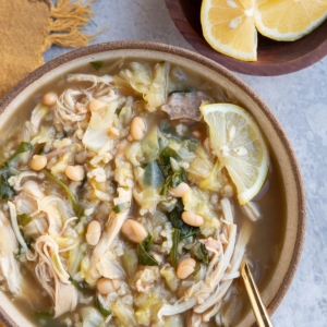 Big bowl of chicken and cabbage soup with a small bowl of sliced lemons.