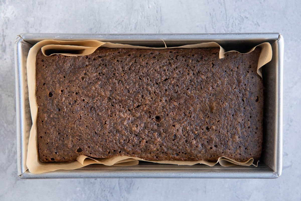 Loaf pan with gingerbread loaf inside, fresh out of the oven and ready to eat.