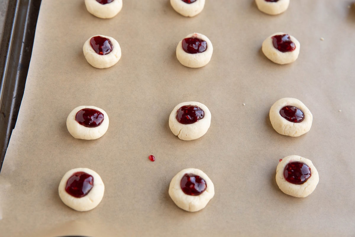 Shortbread cookie dough filled with raspberry jam to make raspberry thumbprints.