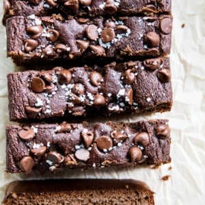 Loaf of chocolate banana bread cut into individual slices. Chocolate chips and sea salt are sprinkled on top.
