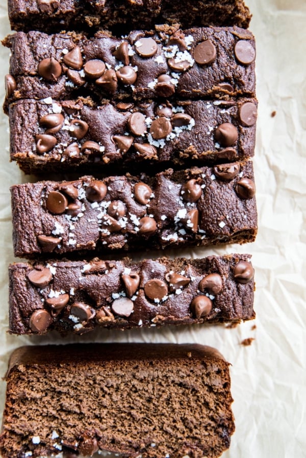 Loaf of chocolate banana bread cut into individual slices. Chocolate chips and sea salt are sprinkled on top.