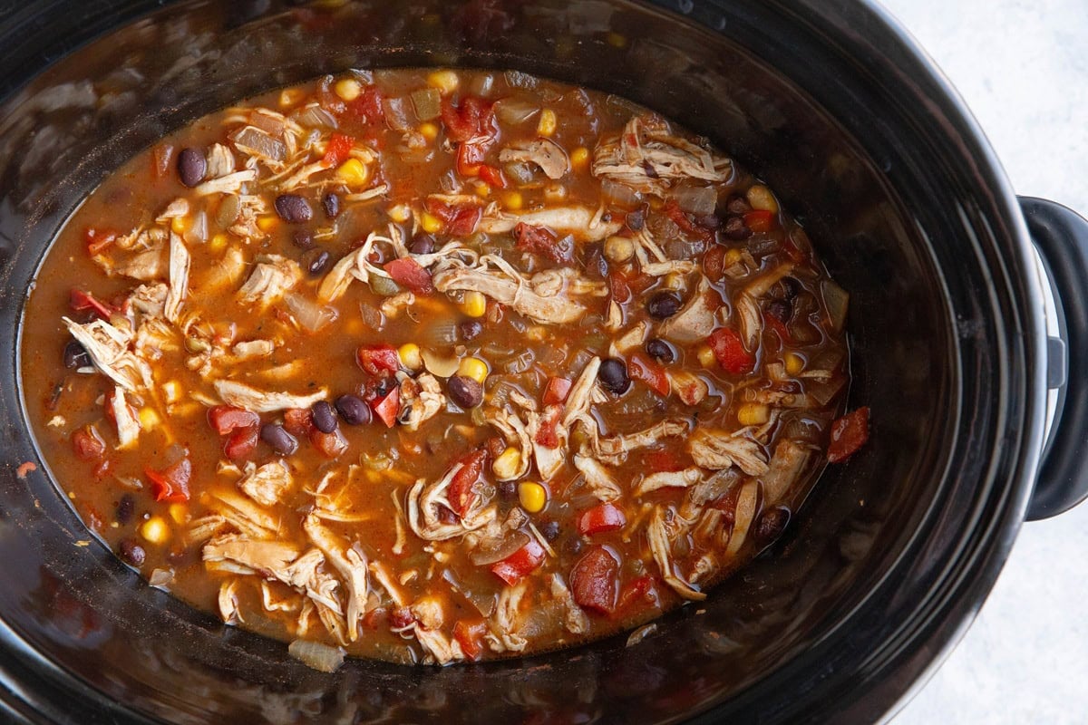 Slow cooker full of shredded chicken chili, ready to eat.