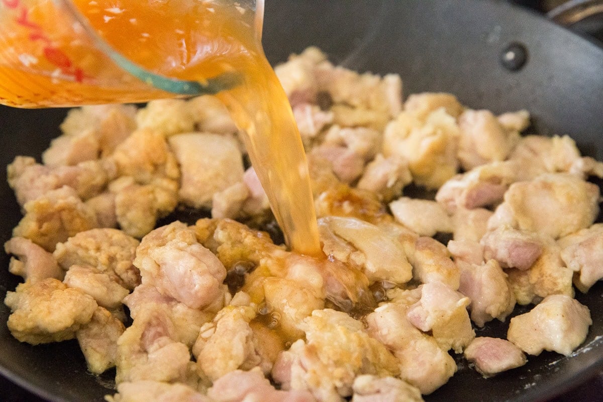 Pouring the lemon sauce into the skillet with the browned chicken.