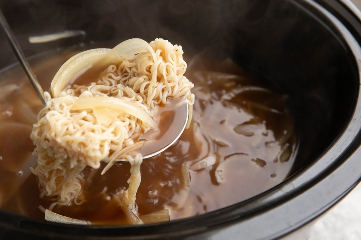 ladle scooping ramen out of a slow cooker.