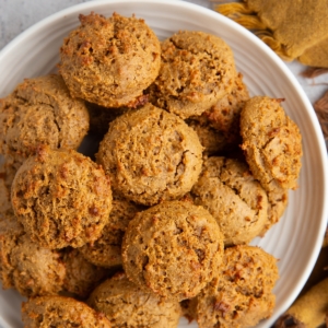 Plate full of peanut butter cookies and a small bowl of peanut butter to the side with a golden napkin. Ready to serve.