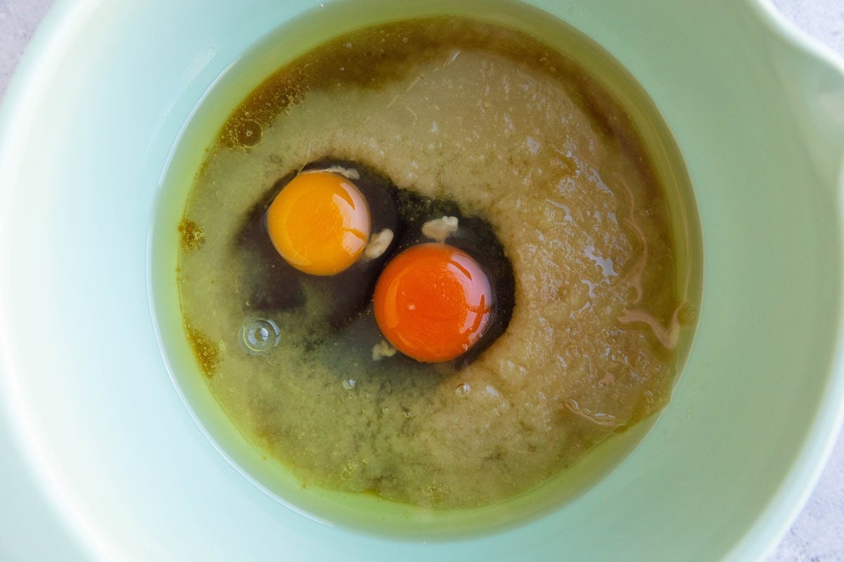 Applesauce, eggs, oil, and pure maple syrup in a mixing bowl for carrot ginger cake.