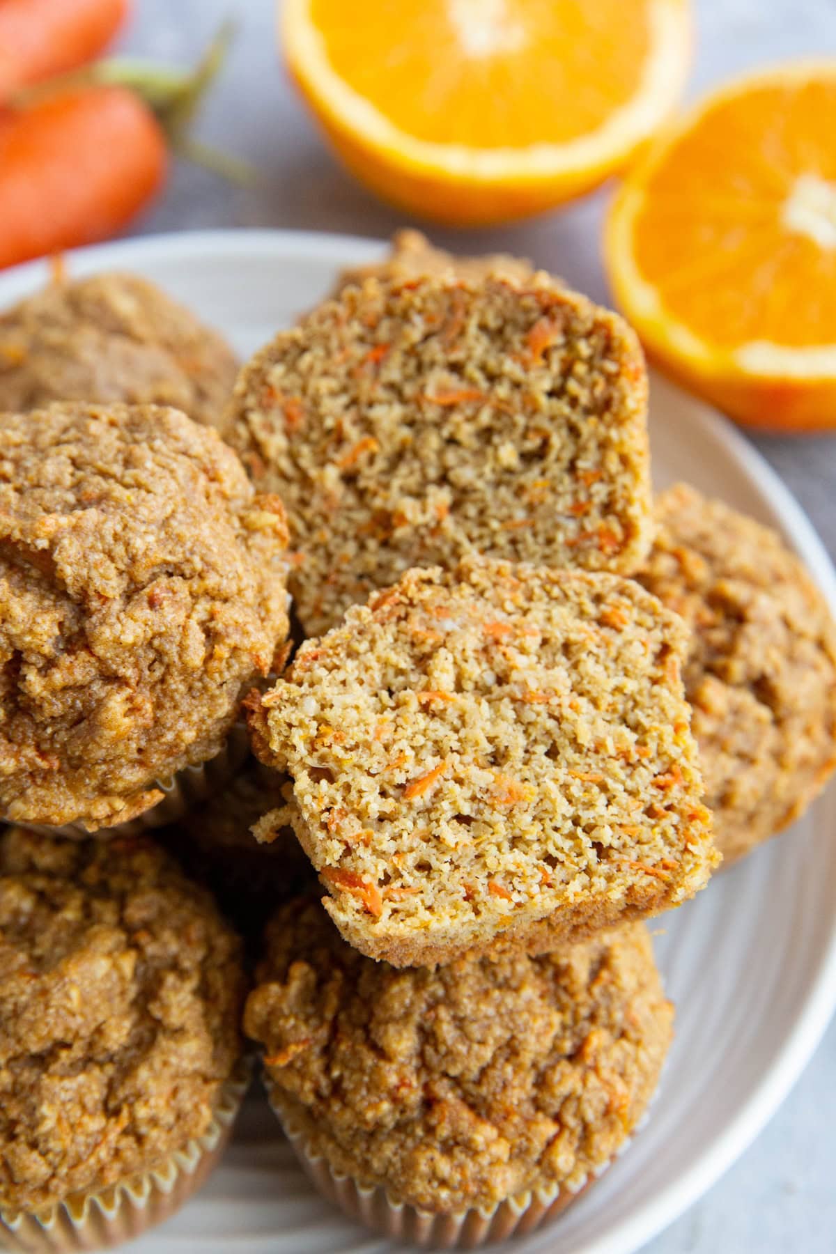 Plate full of carrot ginger orange muffins with one sliced in half.